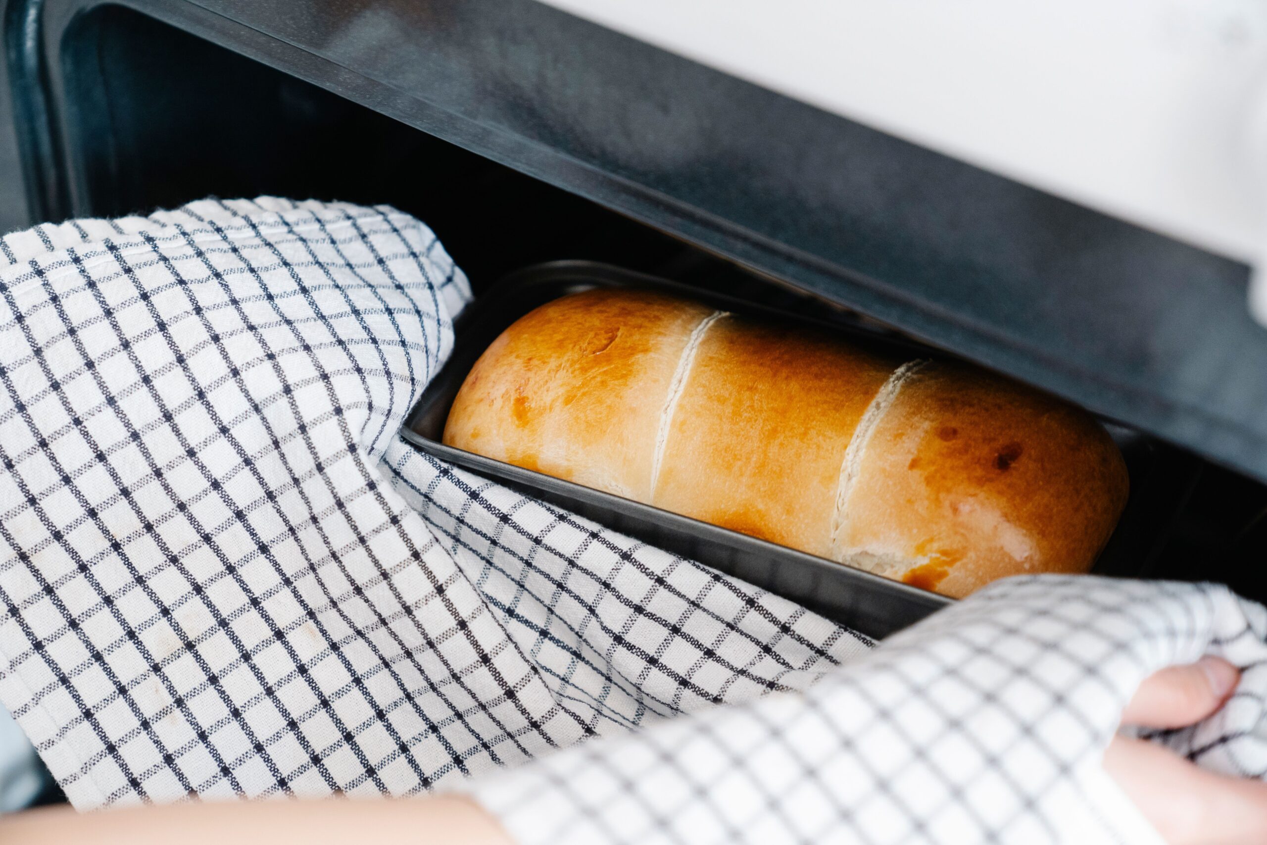 Freshly baked homemade bread loaf being removed from a pan