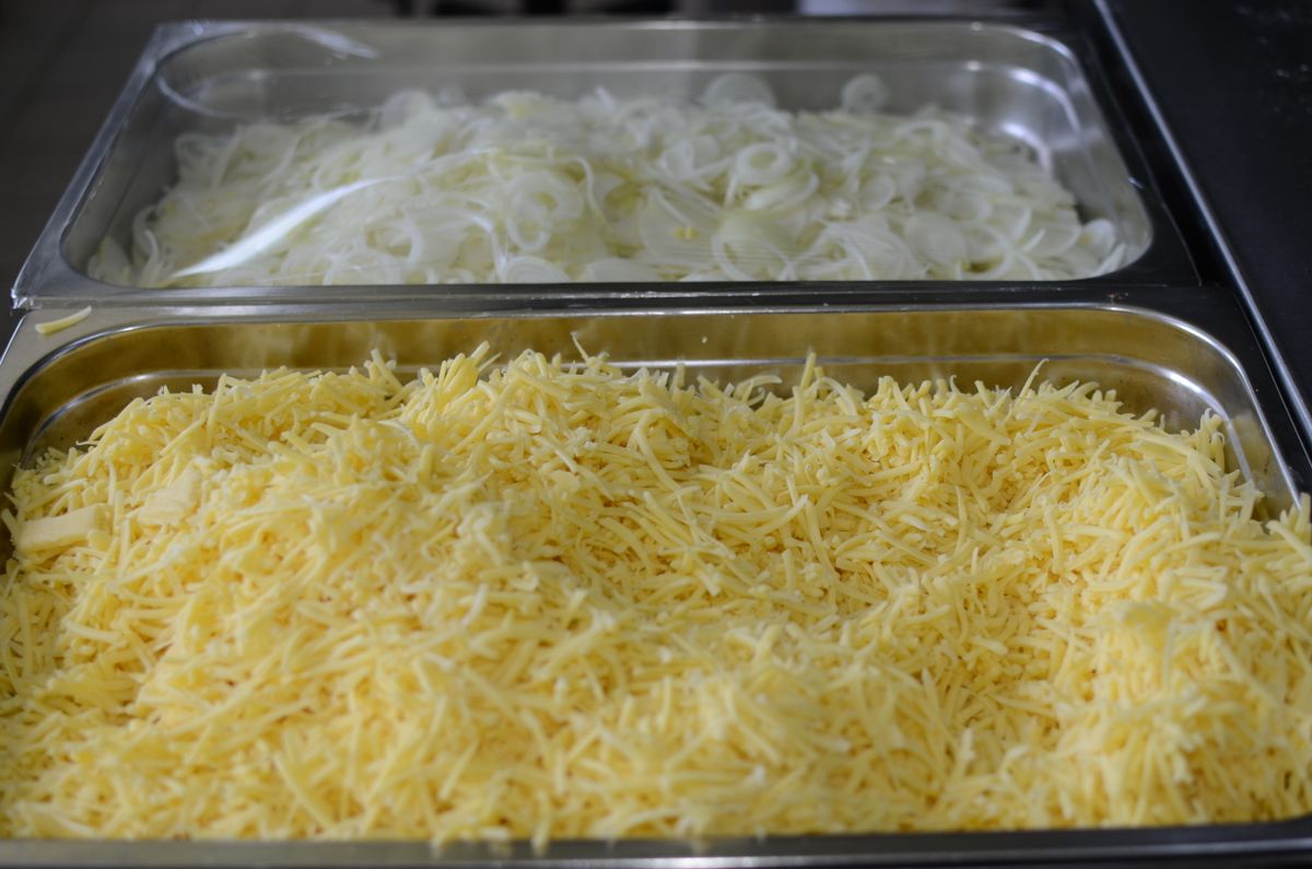 Freshly shredded cheese in metal prep trays