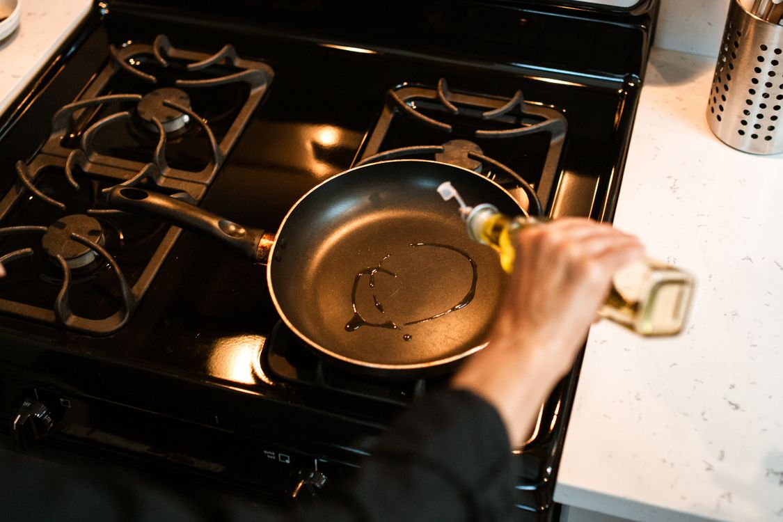 Pouring oil into a nonstick frying pan on a stovetop