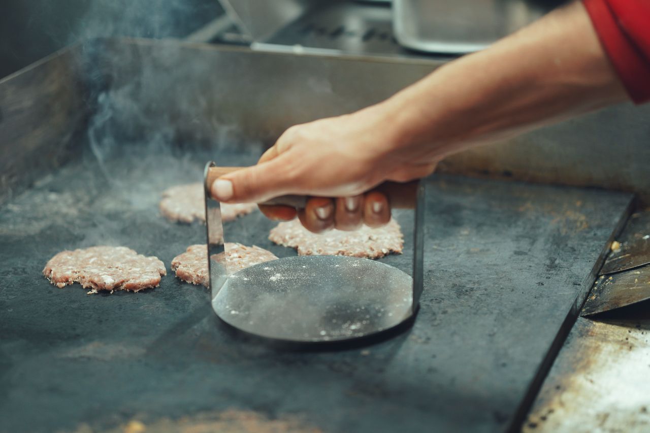 Pressing smash burgers on a hot flat top griddle