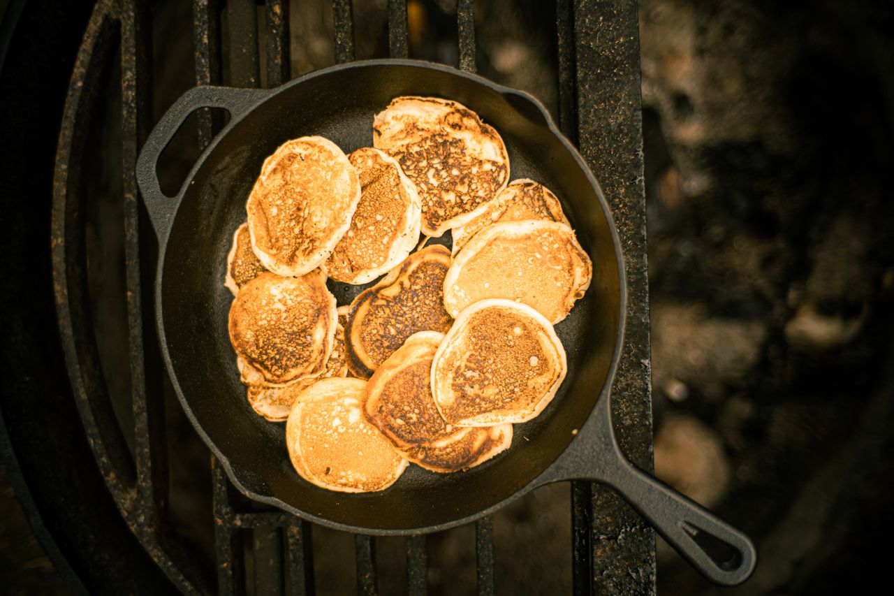 Pancakes cooking in a cast iron skillet over a fire