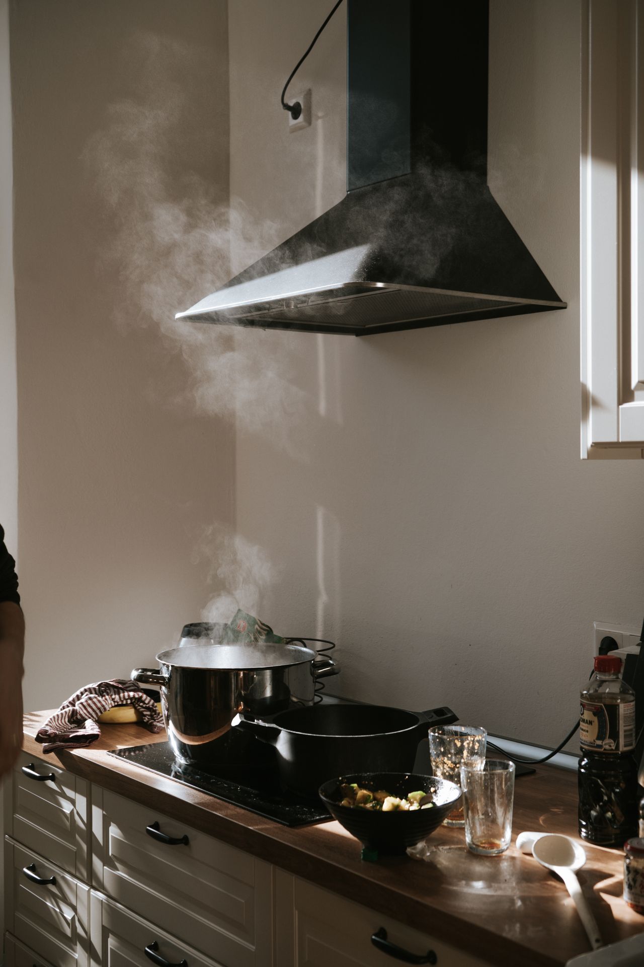 A range hood capturing steam rising from a pot on the stove