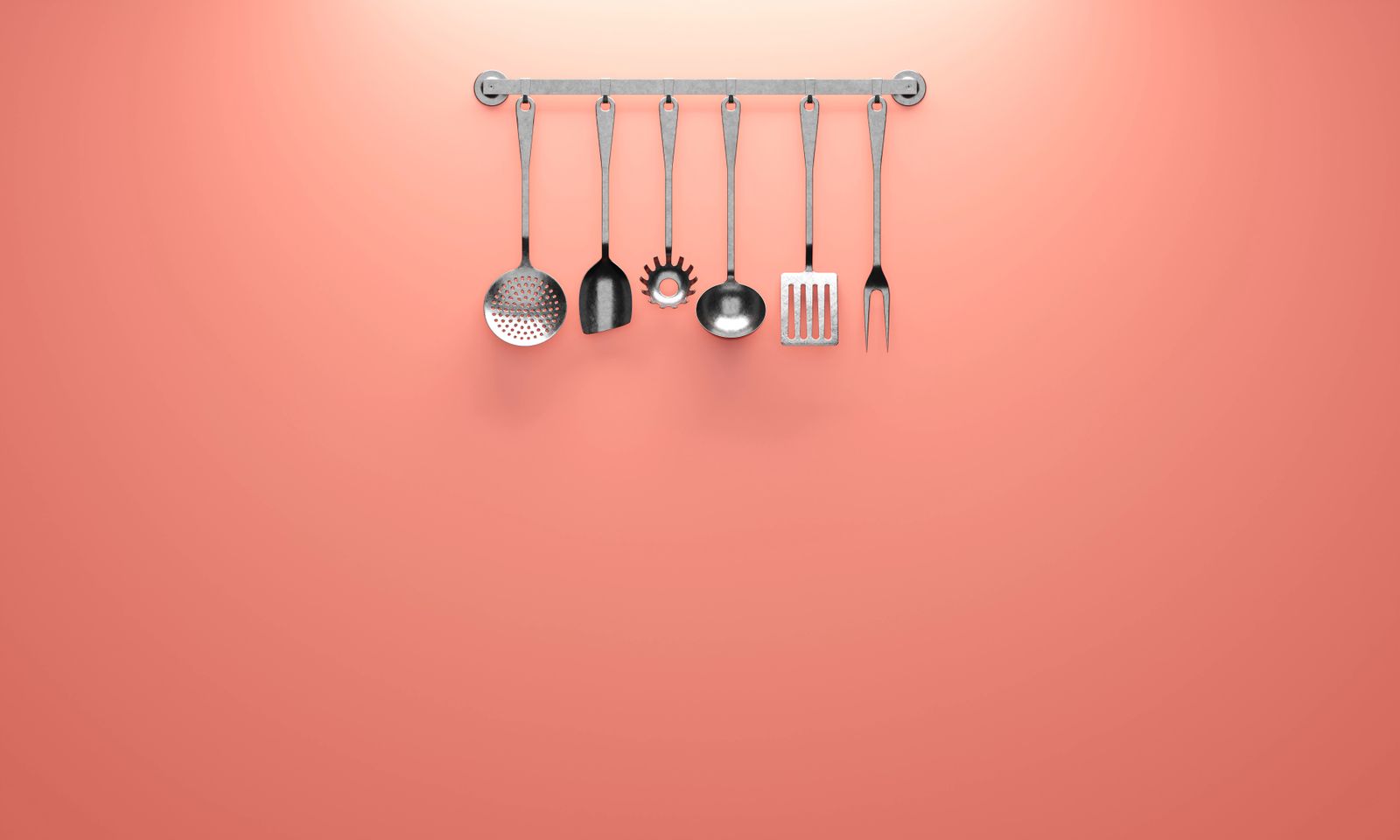 Stainless steel kitchen utensils hanging on a rail, representing the essential tools every kitchen needs