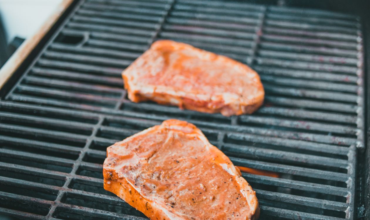 Two steaks grilling outdoors, comparing wireless meat thermometers
