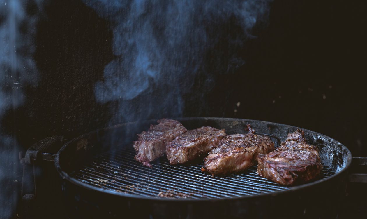 Steaks grilling on a smoky barbecue