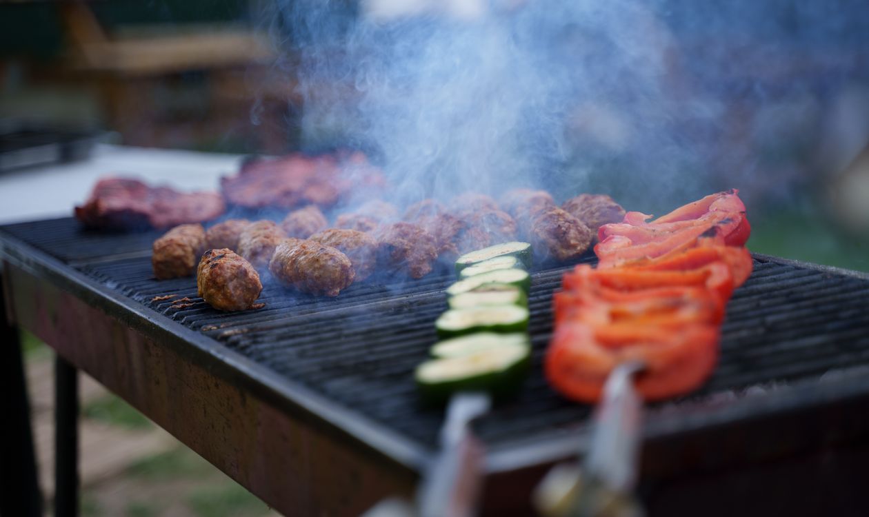 Smoky grill with meats cooking outdoors