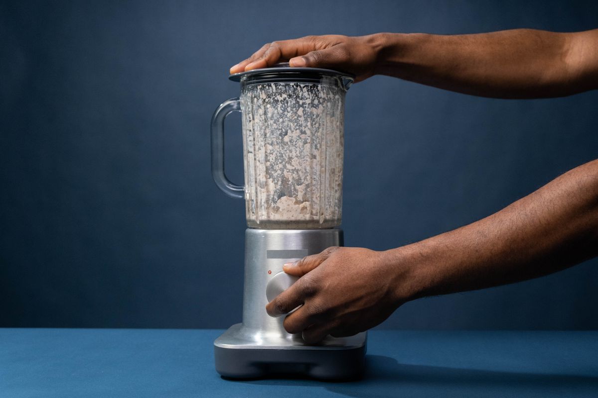 Hands operating a countertop blender in a kitchen