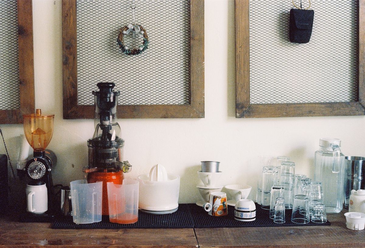 Vertical masticating juicer assembled on a counter beside jugs and glasses