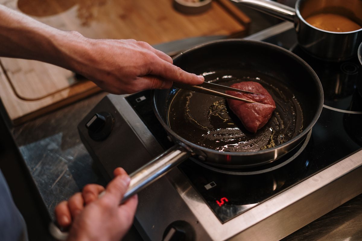 Frying pan resting on a black glass induction cooktop, where a flat base matters most