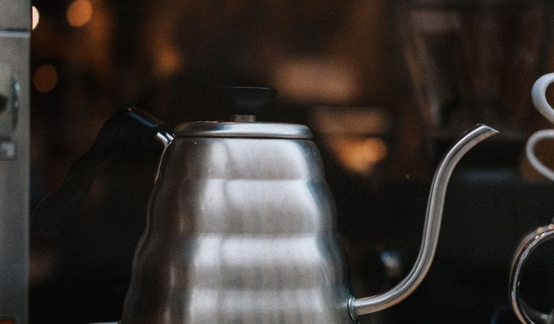 A stainless steel gooseneck kettle on a wooden counter