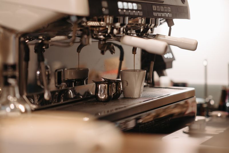 Espresso being pulled from a group head into a small cup on an espresso machine